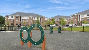 A playground with a green sign that says "Oak Grove" in front of apartment buildings.